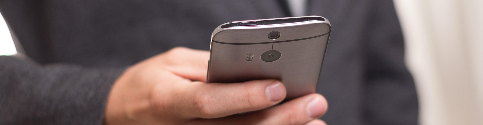 Person holding a smartphone in a professional setting, highlighting secure mobile device use and modern cybersecurity practices.